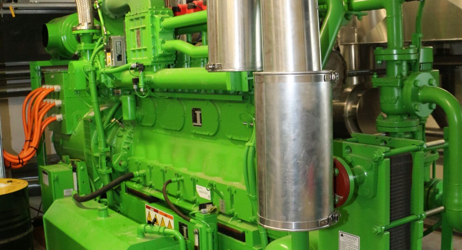 Die jüngste BHKW-Einheit, ein zweiter Gasmotor mit mehr Leistung (grün), liefert seit 2021 zusätzlichen Strom ins Netz und ist nun dritter Wärmeerzeuger der Müller Energie GmbH für das Nahwärmenetz.
